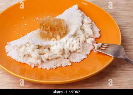 Casabe (ingaggiami, beiju, bob, biju) - flatbread di manioca (tapioca) con ricotta e miele sulla piastra su sfondo di legno. Messa a fuoco selettiva Foto Stock