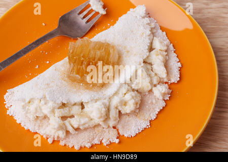 Casabe (ingaggiami, beiju, bob, biju) - flatbread di manioca (tapioca) con ricotta e miele sulla piastra su sfondo di legno. Messa a fuoco selettiva Foto Stock