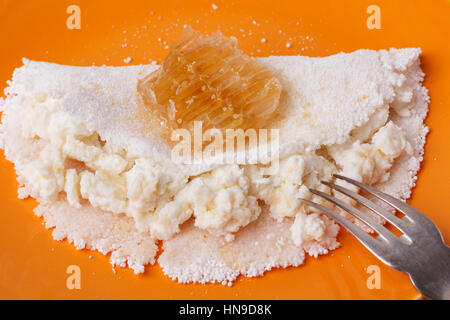 Casabe (ingaggiami, beiju, bob, biju) - flatbread di manioca (tapioca) con ricotta e miele sulla piastra su sfondo di legno. Messa a fuoco selettiva Foto Stock