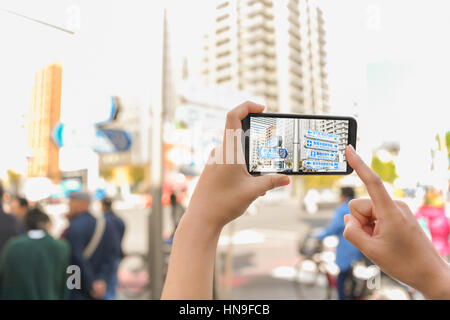 Donna Giapponese utilizzando augumented reality app sullo smartphone centro di Tokyo, Giappone Foto Stock