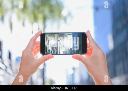 Donna Giapponese utilizzando augumented reality app sullo smartphone centro di Tokyo, Giappone Foto Stock