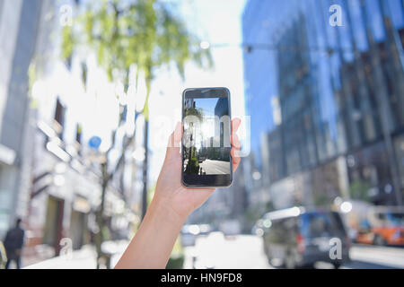 Donna Giapponese utilizzando augumented reality app sullo smartphone centro di Tokyo, Giappone Foto Stock