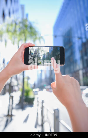 Donna Giapponese utilizzando augumented reality app sullo smartphone centro di Tokyo, Giappone Foto Stock