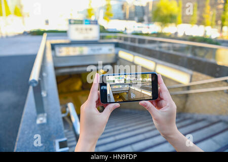 Donna Giapponese utilizzando augumented reality app sullo smartphone centro di Tokyo, Giappone Foto Stock