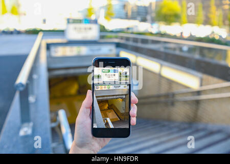 Donna Giapponese utilizzando augumented reality app sullo smartphone centro di Tokyo, Giappone Foto Stock