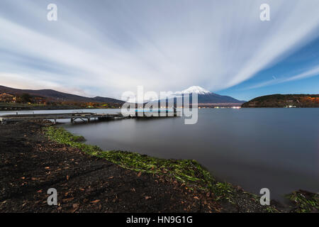 Vista notturna di cielo nuvoloso e il Monte Fuji di notte dal lago Yamanaka, Prefettura di Yamanashi, Giappone Foto Stock