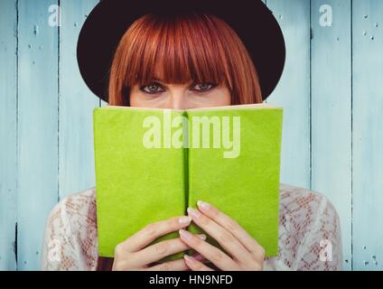 Digital composito della donna con il libro verde contro il blu del pannello di legno Foto Stock