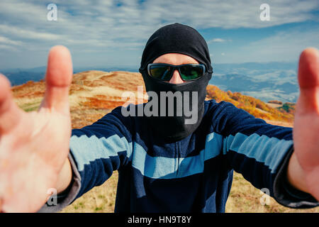 Giovane uomo vestita di nero balaclava guardando la telecamera Foto Stock