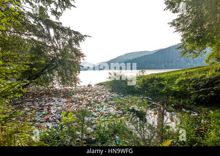 Grande lago in montagna con un sacco di immondizia trash lattine e bottiglie in acqua. Ecologia catastrofe, inquinamento ambientale concetto Foto Stock