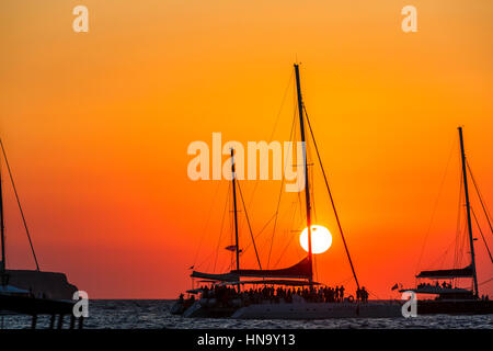 Tramonto sul mare Mediterraneo visitati dai turisti di un catamarano a Baia di Ammoudi, Oia - Santorini, un'isola greca delle Cicladi gruppo Foto Stock