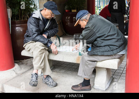 Due uomini anziani giocare a dama mentre su un banco in un parco a Hong Kongtwo vecchio gli uomini giocano a dama mentre su una panchina in un parco di Hong Kong Foto Stock