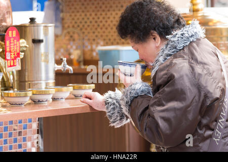 Donna sorseggiando una bevanda calda in un bar tradizionale sulla strada di Mong Kok del distretto di Hong Kong Foto Stock