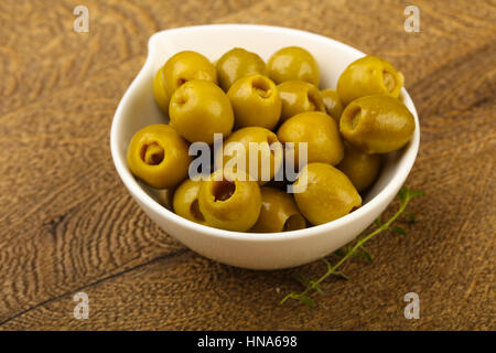 Olive farcite in heap la ciotola su uno sfondo di legno Foto Stock