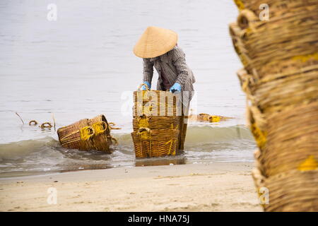 Donna di cestelli di lavaggio su salsa di pesce produzione, Mui Ne, Vietnam Foto Stock