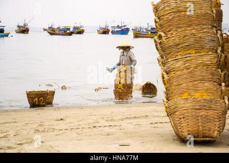 Donna di cestelli di lavaggio su salsa di pesce produzione, Mui Ne, Vietnam Foto Stock