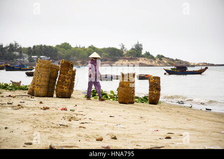 Donna di cestelli di lavaggio su salsa di pesce produzione, Mui Ne, Vietnam Foto Stock