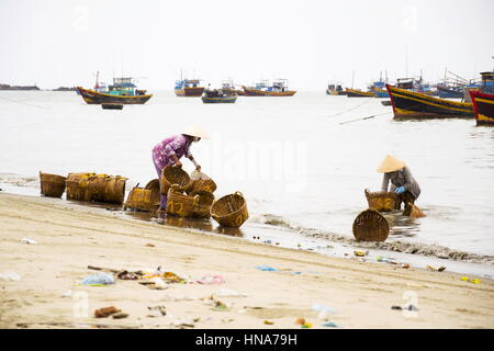 Donna di cestelli di lavaggio su salsa di pesce produzione, Mui Ne, Vietnam Foto Stock