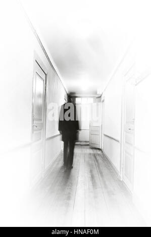 Man in Black, motion blur, passeggiate in un ospedale di bianco coooridor. Foto Stock