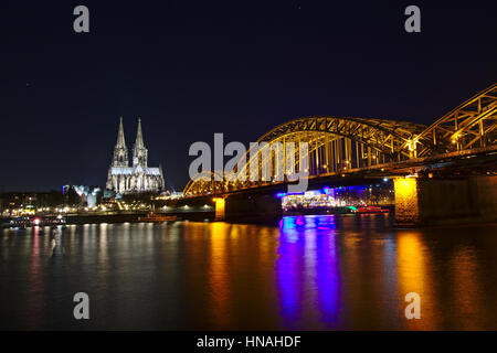 Vista notturna su colonia da sul fiume Reno, con la cattedrale e hohenzollern ponte ferroviario Foto Stock