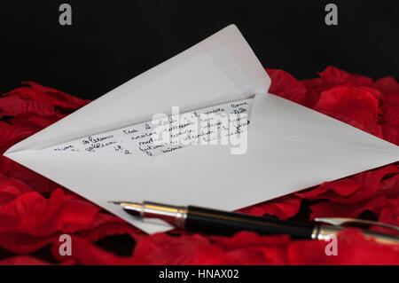 Lettera d'amore su rosso petali di rosa e sfondo nero Foto Stock