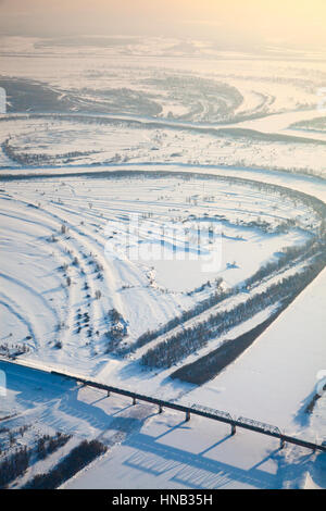 Il treno attraversa il fiume sul ponte in inverno, vista dall'alto Foto Stock