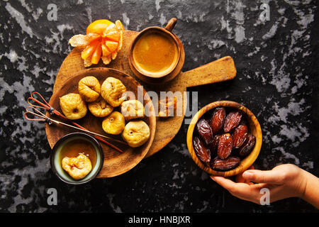 Frutta secca: le figure e le date su una tavola di legno, su sfondo scuro con il caffè. Snack sani, zuccheri naturali Foto Stock