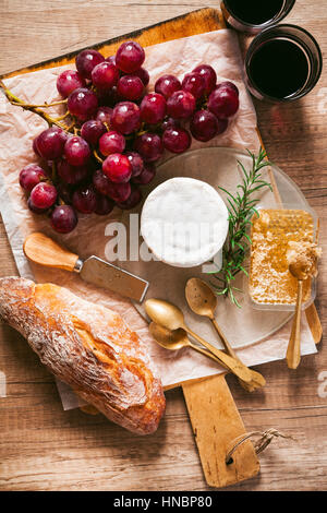 Antipasto di formaggio, uva, vino, miele e il pane su una tavola di legno Foto Stock