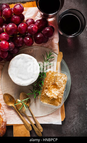 Formaggi e vino. formaggio, uva, vino, miele e pane sulla pietra grigia sullo sfondo Foto Stock