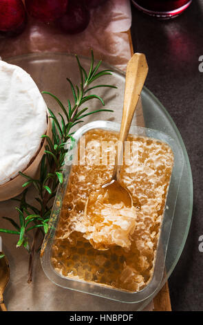 Il miele in favi sul tavolo con un aperitivo di tartine, formaggio e uva. Cucina francese Foto Stock