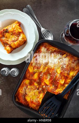 Italiano classico melanzana le lasagne con le verdure e il vino rosso in una teglia su una pietra grigio Sfondo .fuoriuscita di parmigiano, rosmarino, vecchio cucchiaio . Consente di visualizzare Foto Stock
