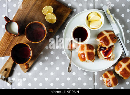 Colazione di Pasqua con i tradizionali hot Cross Bun e marmellata. Da sopra il tavolo in legno. Foto Stock