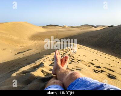 L uomo per le gambe distese sulla duna di sabbia, Spagna Foto Stock