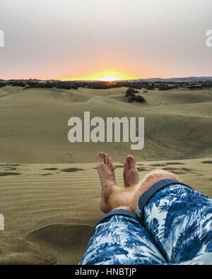 L uomo per le gambe distese sulla duna di sabbia, Spagna Foto Stock