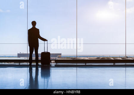 Imprenditore di viaggiatori in aeroporto in attesa del volo e piedi con trolley, business travel Foto Stock