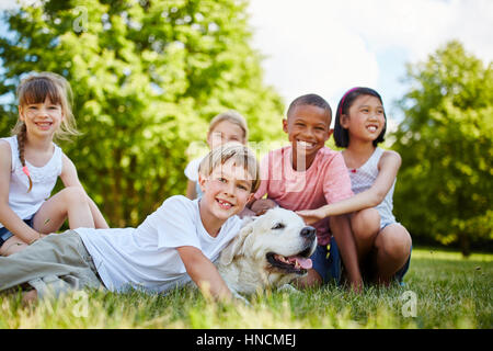 Interracial gruppo di bambini con il Golden Retriever nel parco Foto Stock