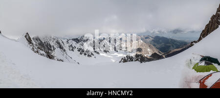 Nuvoloso pano vista da alta montagna con tende a Tian Shan montagne, Kirghizistan Foto Stock