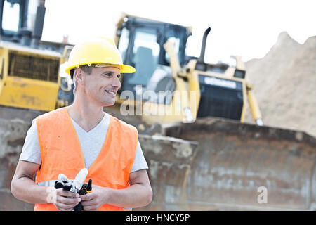 Supervisore sorridente che guarda lontano al sito in costruzione Foto Stock