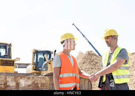 Gli architetti si stringono la mano al sito in costruzione contro il cielo chiaro Foto Stock