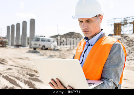 Supervisore utilizzando il portatile in costruzione sul sito giornata di sole Foto Stock