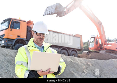 Supervisore utilizzando il portatile in costruzione sul sito giornata di sole Foto Stock