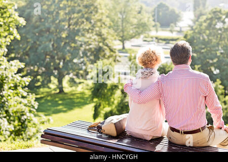 Vista posteriore di mezza età giovane relax su una panchina nel parco Foto Stock