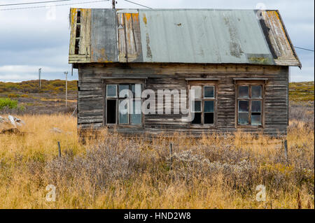 In legno antico casa decrepita che necessitano di riparazione con tetto danneggiato e finestre rotte Foto Stock