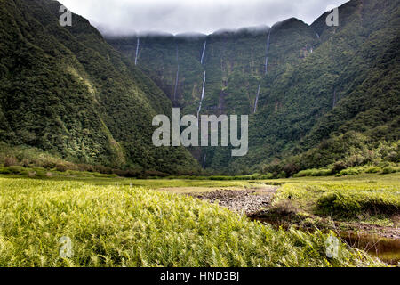 La Reunion Island le grand etang valley con cascate e montagne lussureggianti tropicali prato verde paesaggio di nuvole Foto Stock
