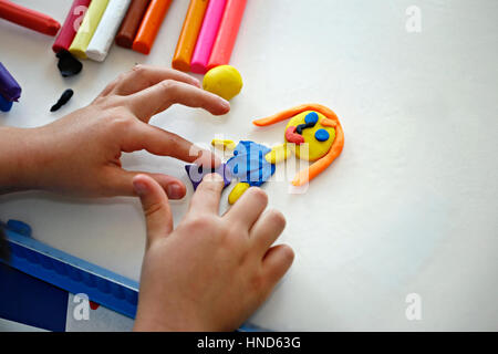 Le mani della bambina rendendo la bambola dal coloratissimo impasto di argilla (plastilina) Foto Stock