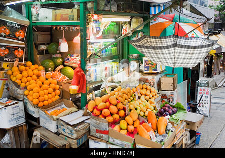 Uomo di lettura, greengrocery, Graham Street Market,centralissima Soho,Hong Kong, Cina Foto Stock