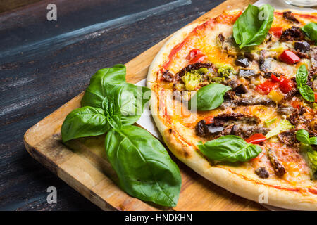 Pizza Fresca servita su un tavolo di legno. Profondità di campo. Foto Stock