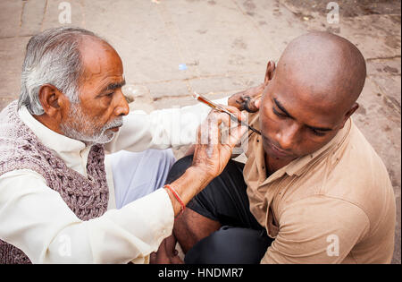 Barbiere della rasatura della testa e della barba di pellegrino Dashashwamedh ghat (principale ghat), nel fiume Gange, Varanasi, Uttar Pradesh, India. Foto Stock