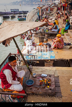 Un Pandits (uomo santo e il sacerdote che compie cerimonie) in attesa per i clienti, sul ghats del fiume Gange, Varanasi, Uttar Pradesh, India. Foto Stock