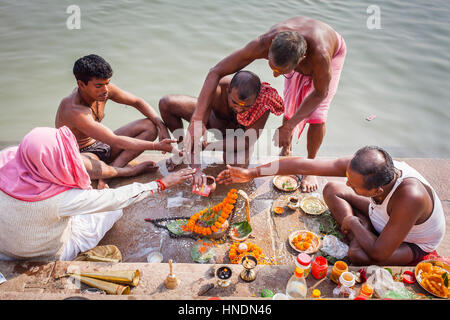 Pellegrini facendo una offerta rituale e pregando, ghats del fiume Gange, Varanasi, Uttar Pradesh, India. Foto Stock