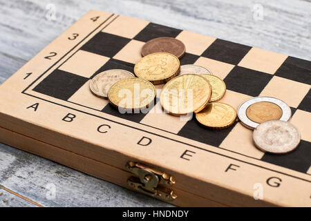 Monete sulla scacchiera di legno. Foto Stock